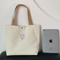Borsa in tela color crema con manici marroni e toppa con cane carino accanto a un iPad - Beige