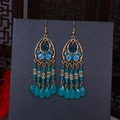 Detailed macro of Bohemian teardrop fringe earrings with blue beads and golden flowers - Gold Cyan Blue