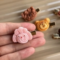 Primer plano de una pinza de pelo de perrito rosa con textura de crema y clip dorado - Caniche