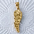 Close-up of golden wing pendant with detailed feather texture on white ceramic base - Wing / Gold