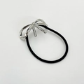 Detail van zwarte haarelastiek met een gepolijst zilveren metalen strik accessoire - Zilver