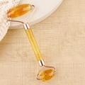 Dual-headed amber facial roller with rose gold frame on a wooden surface - Resin Double Head Roller Transparent Yellow