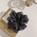 Detailansicht eines Houndstooth-Organza-Scrunchie auf einer Kraftbox mit sanftem Schatten - Hahnentritt Schwarz