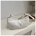 Detail of white pleated crescent underarm bag with adjustable silver buckle on a table - White