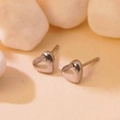 Macro shot of silver heart stud earrings made of polished steel on a natural stone surface - Silver Heart Studs