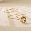 Macro shot of a pear-cut clear gemstone pendant on a fine gold-tone chain necklace - Clear Teardrop Style (BD024-white)