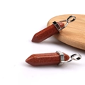 Polished brown goldstone hexagonal point pendants with silver metal loop on wooden base - Gold Sandstone