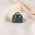 Macro shot of dark green jade handbag pendant with a golden handle on beige fabric - Qinghai Jade