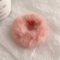Detailopname van een zachte roze pluche haarelastiek met pluizige textuur op wit papier - Lotusroze
