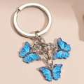 Metal keychain with three blue enamel butterfly pendants on a soft pink background - Sky Blue