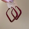 Close-up of burgundy square geometric earrings held on a kraft paper display card - Burgundy