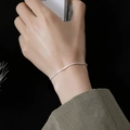 Dettaglio ravvicinato di una catena in argento 925 scintillante indossata sul polso su nero - Bracciale / Argento