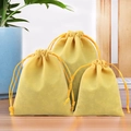 Yellow velvet drawstring jewelry pouches in three sizes on a wooden background - Yellow
