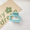 Top view of a light blue square hair claw clip on a white background with a floral card - Matte Small Square Sky Blue