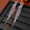 Vue détaillée de boucles d'oreilles à pompons en strass rose avec un motif de nœud - Style Irrégulier Violet