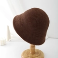 Detail shot of a dark brown knitted bucket hat on a minimalist wooden display stand - Brown