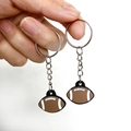 Dettaglio di un portachiavi a forma di palla da rugby marrone con cuciture bianche e anello - Palla da rugby