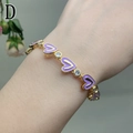 Macro detail of gold bracelet featuring purple enamel hearts and sparkling zircon stones - Light Purple