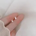 Close-up of minimalist S925 sterling silver rabbit stud earrings on fingertips - Little Rabbit / Silver