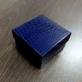Detail view of square navy blue crocodile texture jewelry gift box on dark wood surface - Blue Crocodile Pattern