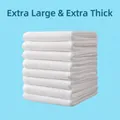 Thickened white disposable travel bath towels stacked neatly on light blue background - Economy Bulk (Extra Thickened)