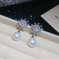 Detalle de elegantes pendientes de copo de nieve con perlas y circonitas en joyero de lujo - Plata (Aguja de Plata S925)