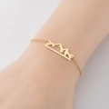 Pulsera dorada de acero inoxidable con colgante de montaña hueco en una muñeca - Dorado