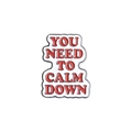 Detail of metal pin with red lettering 'YOU NEED TO CALM DOWN' on white enamel - YOU NEED TO CALM DOWN