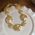 Detalle de un collar de eslabones ovalados irregulares dorados en bandeja cerámica - Collar - Dorado