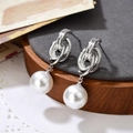 Boucles d'oreilles anneaux entrelacés en argent avec perles blanches sur tissu gris - Argenté