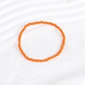 Detailed close-up of a vibrant orange seed bead bracelet on a white textured background - Orange