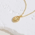 Dettaglio del ciondolo Madonna dorato con intarsio in zircone su sfondo di roccia bianca - Vergine Maria Ovale / Oro