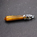 Hexagonal tiger eye stone pendant with polished silver alloy clasp on black surface - Tiger's Eye