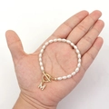 Elegant pearl bracelet with gold OT clasp and zircon M initial pendant on palm - Letter A / Rice Grain Pearl (Copper Zirconia)