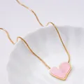 Elegant gold titanium necklace with a pink resin heart pendant on white ceramic plate - Pink Heart