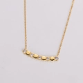 Dettaglio macro di collana dorata con cinque ciondoli esagonali e pietre di zircone - Oro