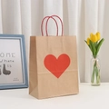 Close-up of brown kraft gift bag with red heart print and red twisted rope handles - Kraft Red Large Heart (21x15x8cm)