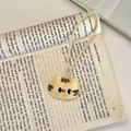 Dettaglio di un ciondolo a testa di gatto in peluche giallo con strisce su un libro - Gatto