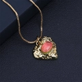 Detailaufnahme eines goldenen Herzanhängers mit einem ovalen rot-grünen Edelstein - Box Kette / Orange