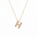 Macro shot of gold H-shaped pendant necklace with micro-paved cubic zirconia stones - Letter H