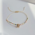 Detailansicht eines Boho-Webarmbands mit bunten Perlen und goldenem Buchstaben-R-Anhänger - Buchstabe R