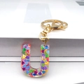 Macro detail of Letter U resin keychain filled with colorful heart-shaped sequins and gold clip - Letter U Lobster Clasp Keychain