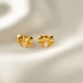 Detailopname van gouden strik oorbellen op witte zijden stof met gepolijste glans - Gouden Bowknot Oorknopjes (r254 Goud)