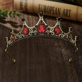 Detailed close-up of a vintage golden tiara with red and black gems on a rustic wooden desk - Bronze Base Red Zirconia