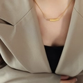 Elegante goldene Titan-Halskette mit gebogenem Stabanhänger getragen von einem Modell - Goldener Unregelmäßiger Stil (P679)
