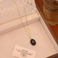 Detail of vintage gold necklace with black oval pendant and red stone in beige jewelry box - Black Agate