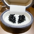 Detailed macro view of black rhinestone floral stud earrings inside a grey velvet jewelry box - Black