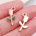 Golden rose flower charms with pink enamel detail held on fingers for size reference - Pink Rose (12317)