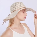 Close-up of beige lace sun hat with hollow floral patterns and brown ribbon tie - Beige