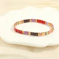 Detailed close-up of handmade Tila bead bracelet with colorful enamel and gold metal spacers - Red & Lavender Set